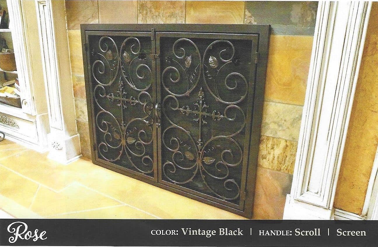 Ornate vintage black custom fireplace doors with scrollwork in a warm stone surround